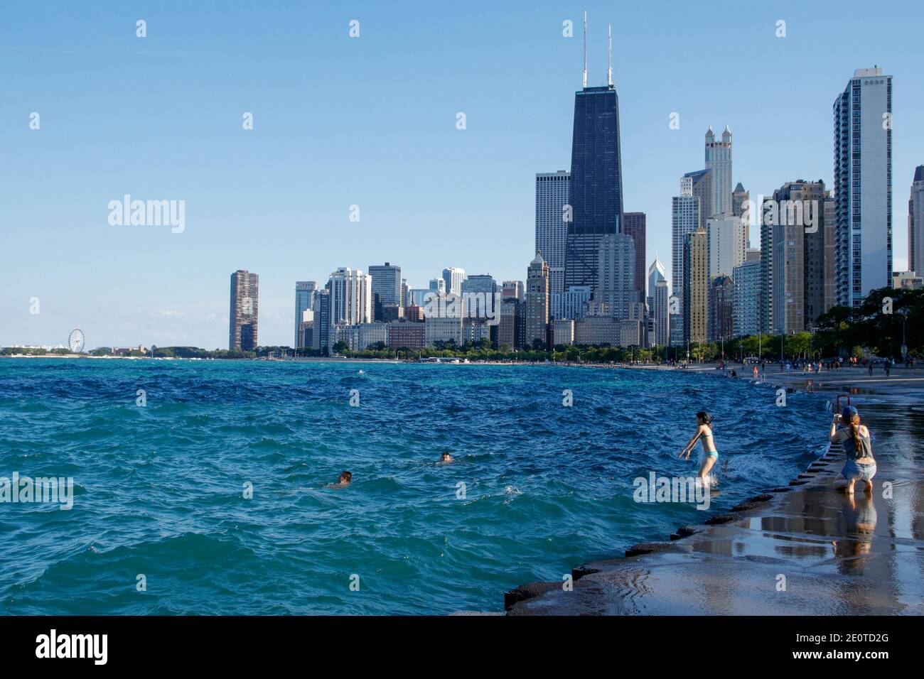 Chicago Seeufer in der Nähe von North Avenue Beach. Junge Frau, die von der Ufermauer in den See springt. Stockfoto
