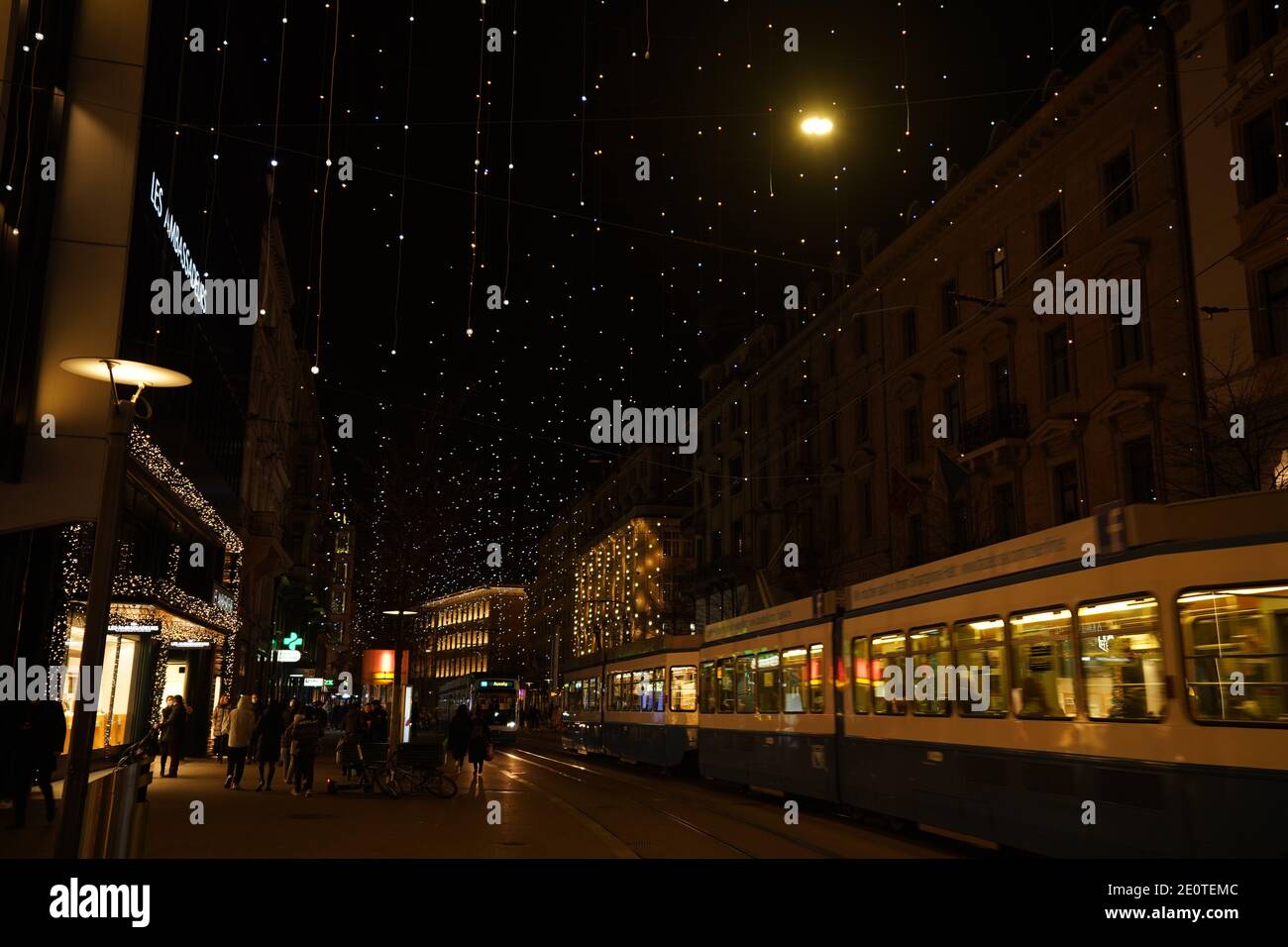 Bahnhofstrasse zur Weihnachtszeit in der Zeit des Corona-Virus. Viele Hängelampen genannt Lucy, Fußgänger und Straßenbahn am Abend. Zürich, 19. Dezember 2020 Stockfoto