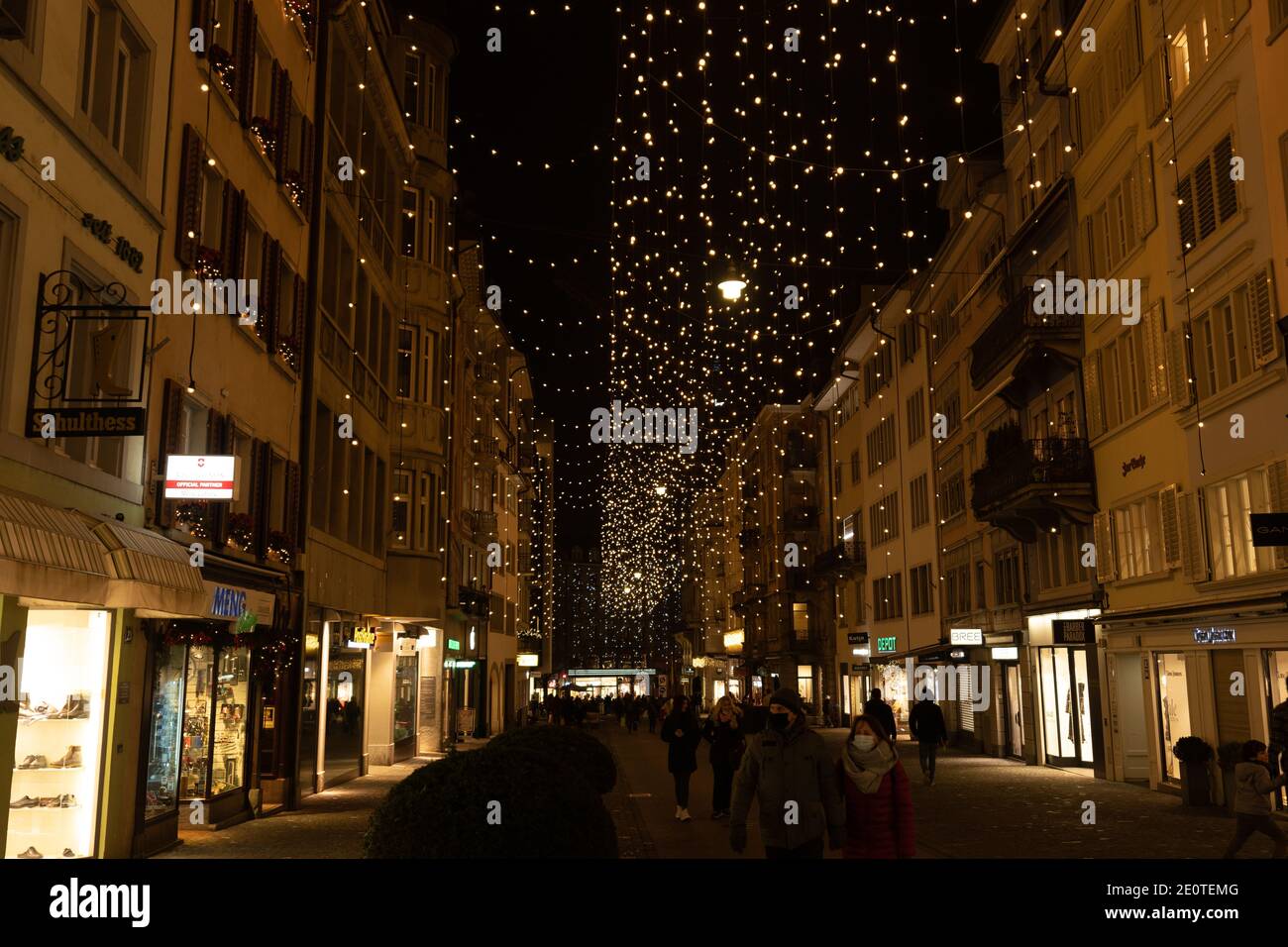 Weihnachtseinkäufe unter den traditionellen Weihnachtslichtern Lucy im Rennweg, einer Seitenstraße der Bahnhofstrasse in Zürich. Fußgänger und alte Gebäude Stockfoto