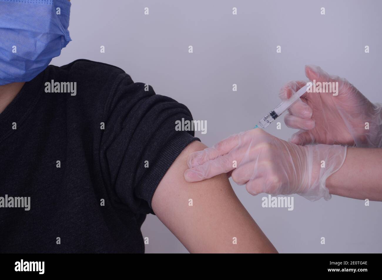 Eine Frauenhand, die eine Spritze vor einem hält Weißer Hintergrund Stockfoto