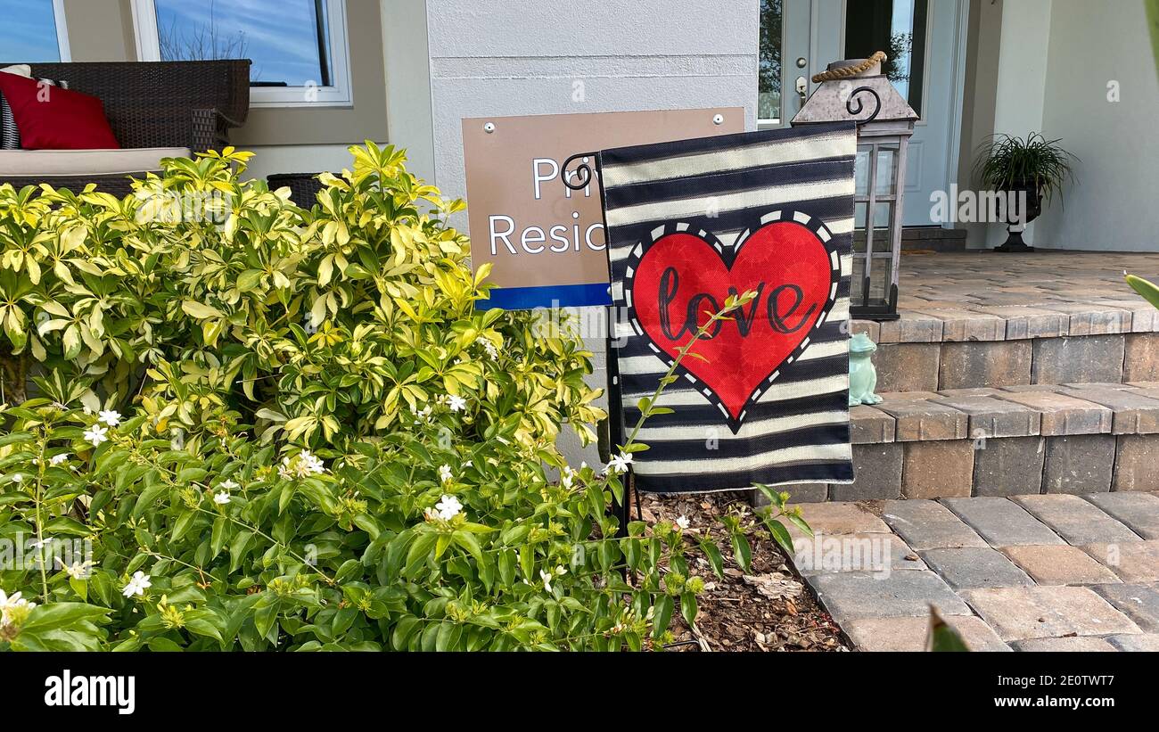 Orlando, FL USA - 23. Januar 2020: Eine Gartenfahne mit Herz, die Liebe in der Mitte vor einem Haus sagt. Konzept Valentinstag, Liebe und roma Stockfoto