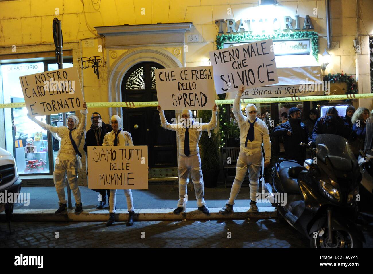 Demonstranten, die wie momies gekleidet sind, halten Plakate mit der Aufschrift "Unser lieber Führer ist zurück" "Wir sind alle Mumien" "Niemand sollte sich um die Anleihespreads kümmern" und "Glücklicherweise ist Silvio hier" vor einem Gebäude, in dem der ehemalige italienische Ministerpräsident Silvio Berlusconi an einer Pressekonferenz zur Präsentation des Fernsehmoderators Bruno teilnimmt Vespas neues Buch in Rom, Italien am 12. Dezember 2012. Silvio Berlusconi bestätigte, dass er bei einer im Februar erwarteten Wahl derzeit noch als Kandidat seiner Partei "People of Freedom" (PDL) stehe. Aber er säte Verwirrung und sagte, er könne seine Wiederwahl aufgeben Stockfoto