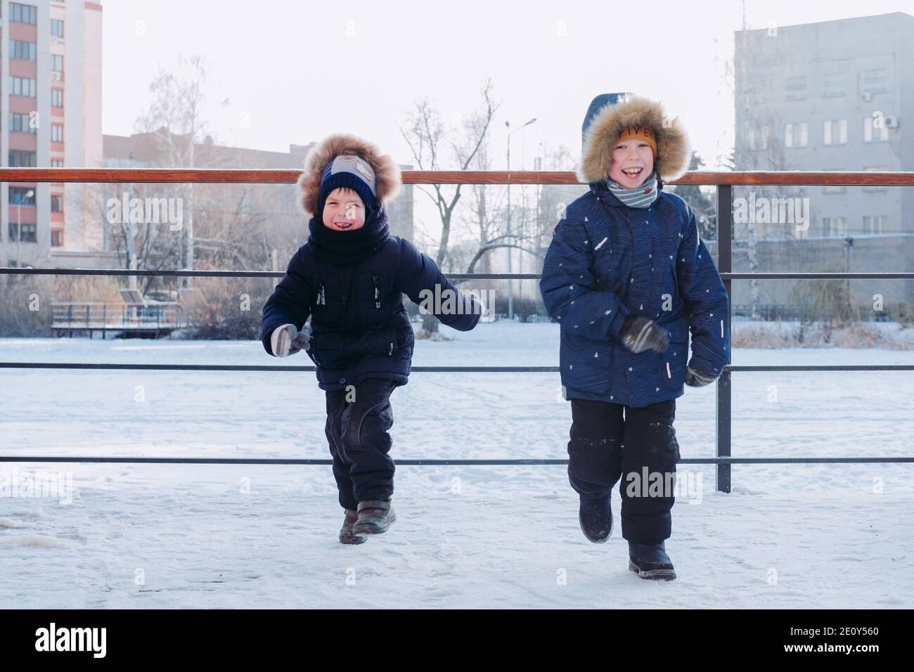 Kinder spielen im Schnee. Glückliche Kinder freuen sich im Winter. Winter Spiele im Schnee. Jungs laufen auf der Straße. Kinder Winterurlaub Stockfoto
