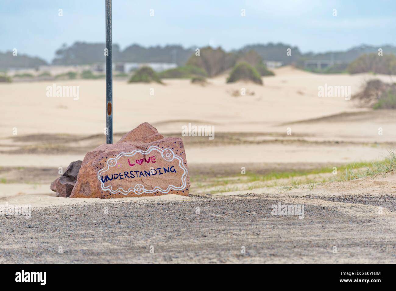 Große Betonbarrieren, die Autos vor Sanddünen am Birubi Beach in Port Stephens, NSW, Australien schützen, sind mit indigenen Botschaften bemalt Stockfoto