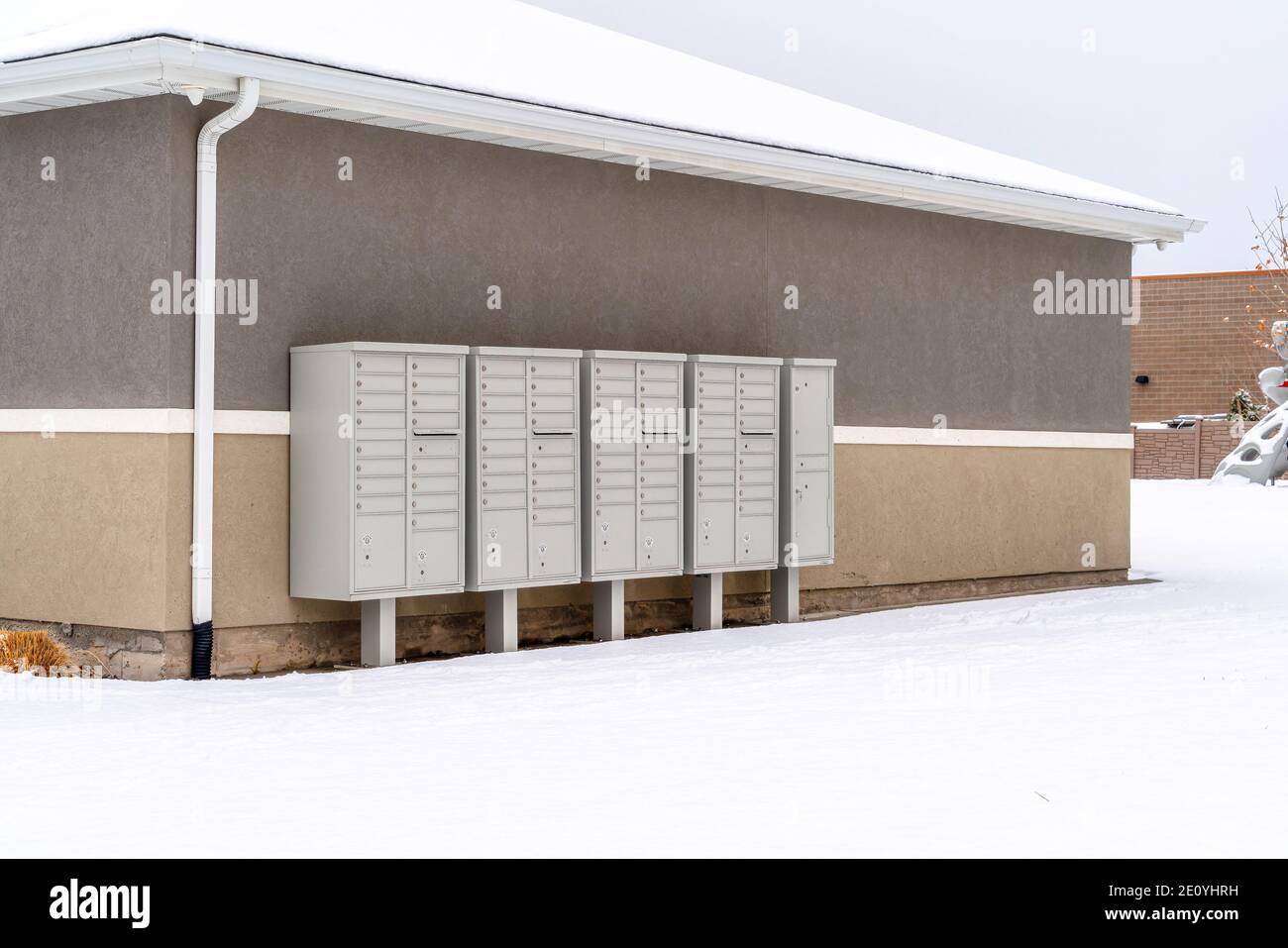Cluster Metallpostfächer mit Sockeln gegen Wand des Gebäudes mit Verschneites Dach Stockfoto