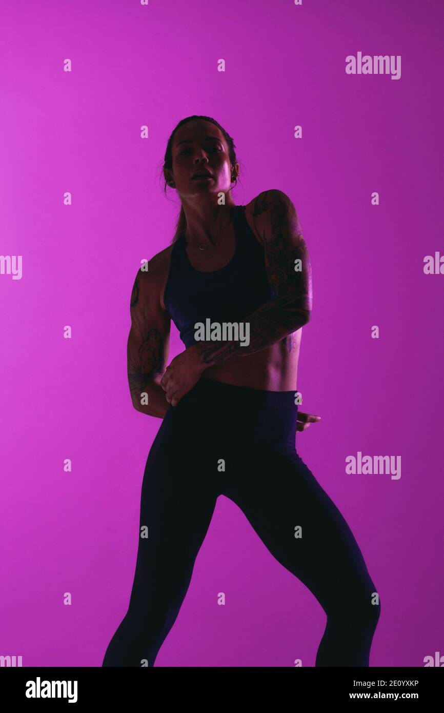 Monochromes Fitness-Porträt von fit Frau Athlet. Frau in Fitness tragen Training auf lila Hintergrund. Stockfoto