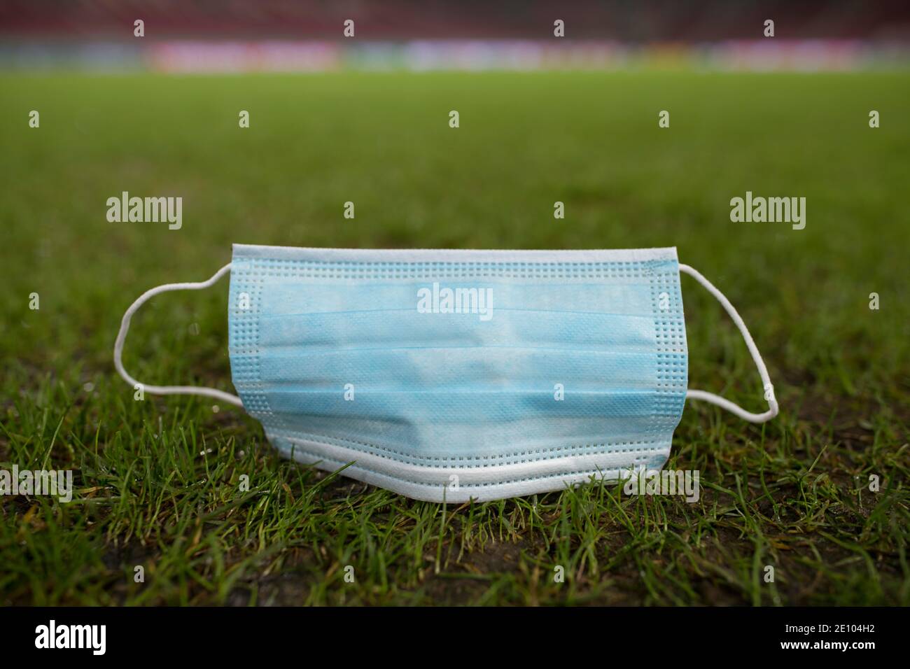 Ausrangierte Gesichtsmaske liegt auf dem Boden auf Gras, Mercedes-Benz Arena, Stuttgart, Baden-Württemberg, Deutschland, Europa Stockfoto