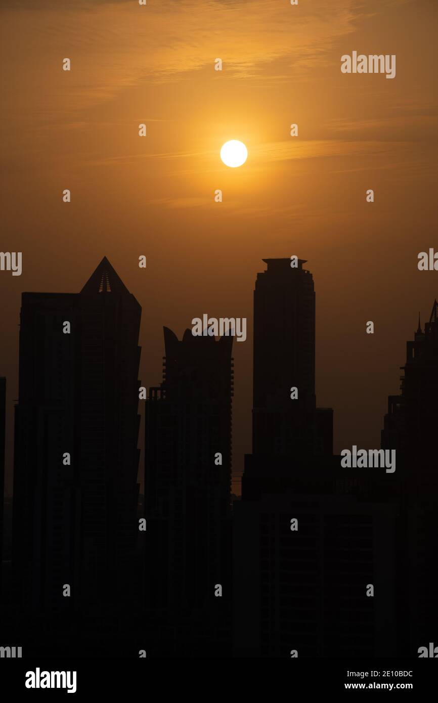 Skyline von Dubai bei Sonnenuntergang mit orangefarbenem und gelbem Himmel über den Wolkenkratzern in den Vereinigten Arabischen Emiraten. (Hochformat) Stockfoto