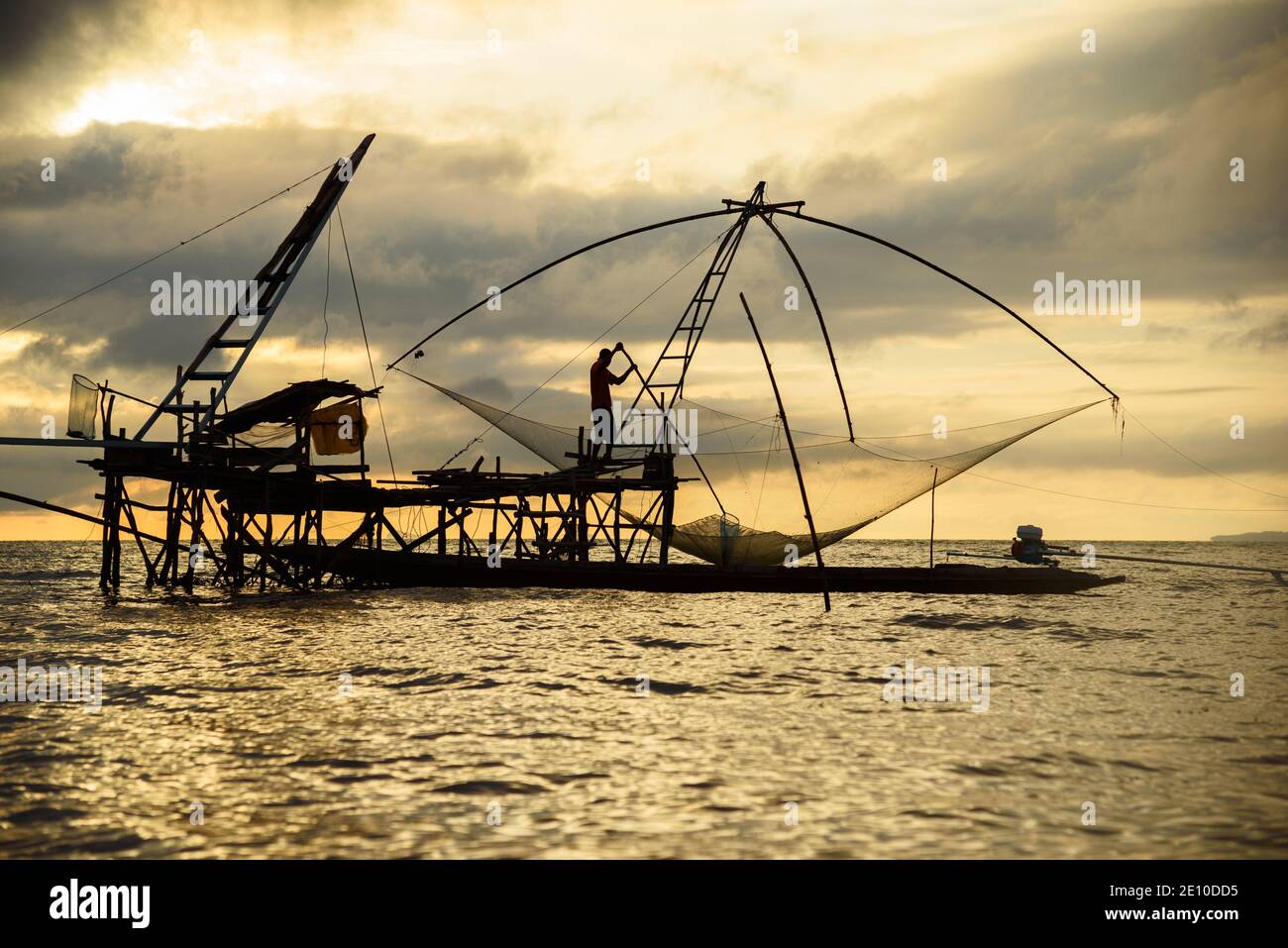 Silhouette eines Fischers, der an einem riesigen quadratischen Fischnetz in Pakpra, Provinz Phtthalung, Thailand arbeitet. Stockfoto