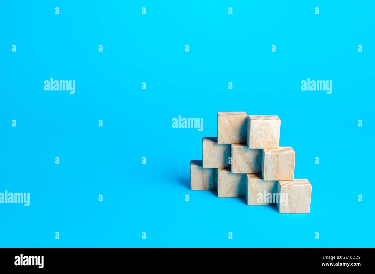 Holzblöcke Pyramide auf einem blauen Hintergrund. Folie für Präsentation. Platz kopieren, für Text platzieren. Schritte. Minimalismus. Einfache Formen Geometrie. Stockfoto