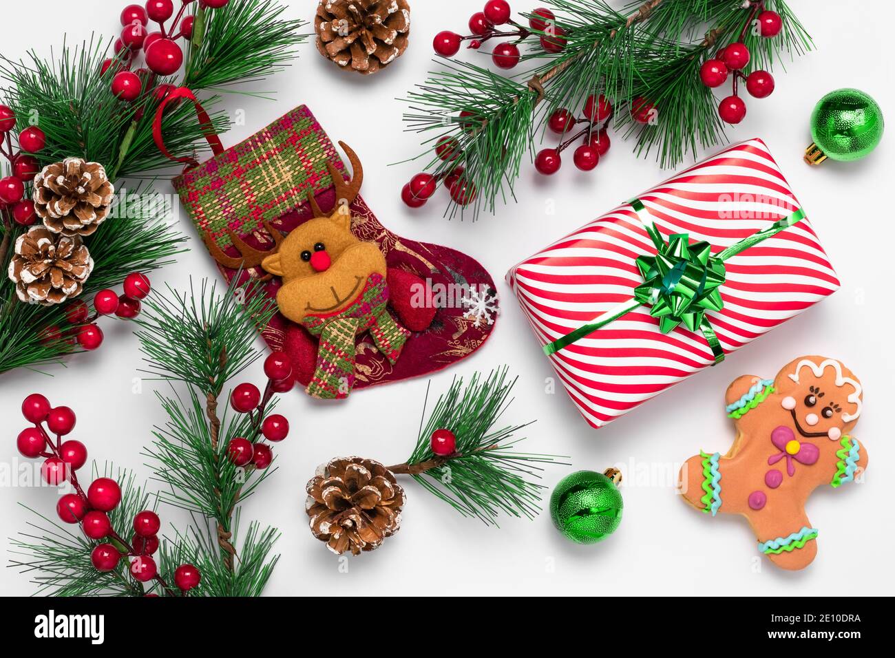 Weiße Weihnachtskarte mit Lebkuchenmann und Strumpf mit Filzrentier verziert. Festliches Neujahr Hintergrund. Kekse und Dekorationen aus gr Stockfoto