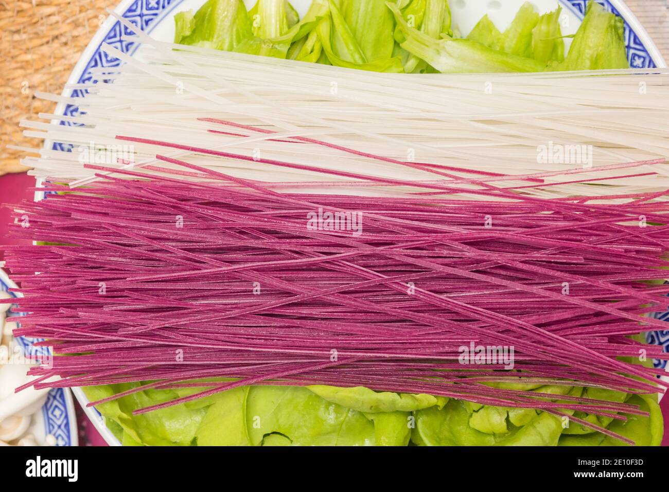 Trockene chinesische Nudeln, gefärbt mit violetter Süßkartoffel auf grünem Salat Stockfoto