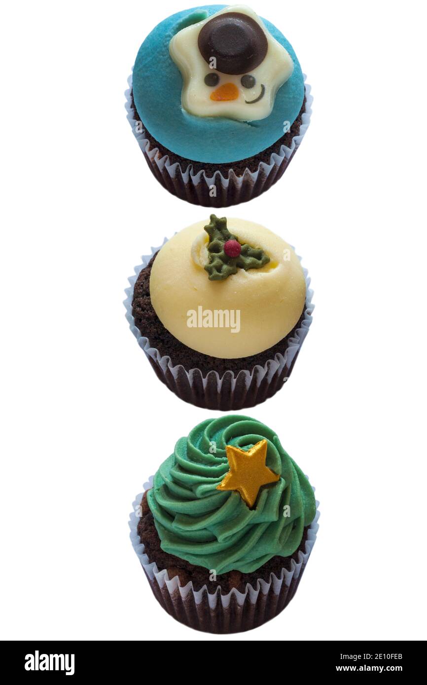 Weihnachtsbaum, Schneemann & Christmas Pudding Cupcakes Cup Cakes in einer Reihe, in einer Linie, M&S Mini festliche Cupcakes isoliert auf weißem Hintergrund Stockfoto