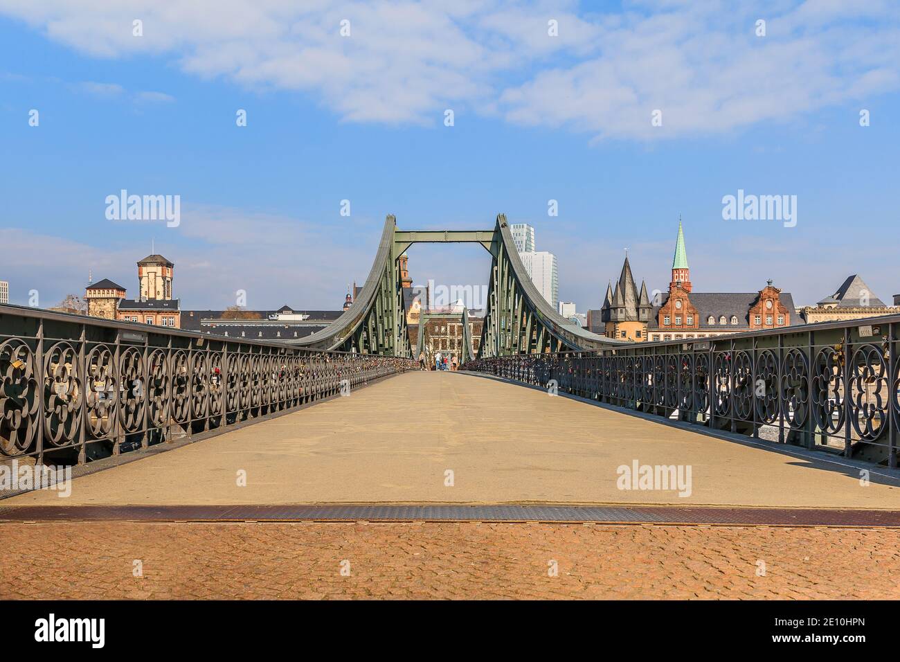 Historische Fußgängerbrücke über den Main in Frankfurt. Eisenbrücke tagsüber mit wenigen Leuten. Häuser der Altstadt im Hintergrund mit Sunshi Stockfoto