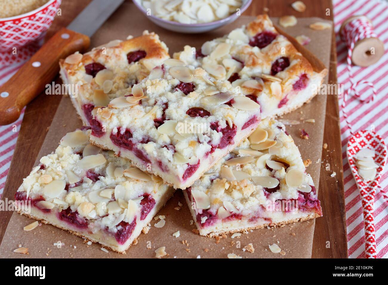 Kirschkäse-Kuchen mit Krümel und Mandeln auf Holzbrett Stockfoto