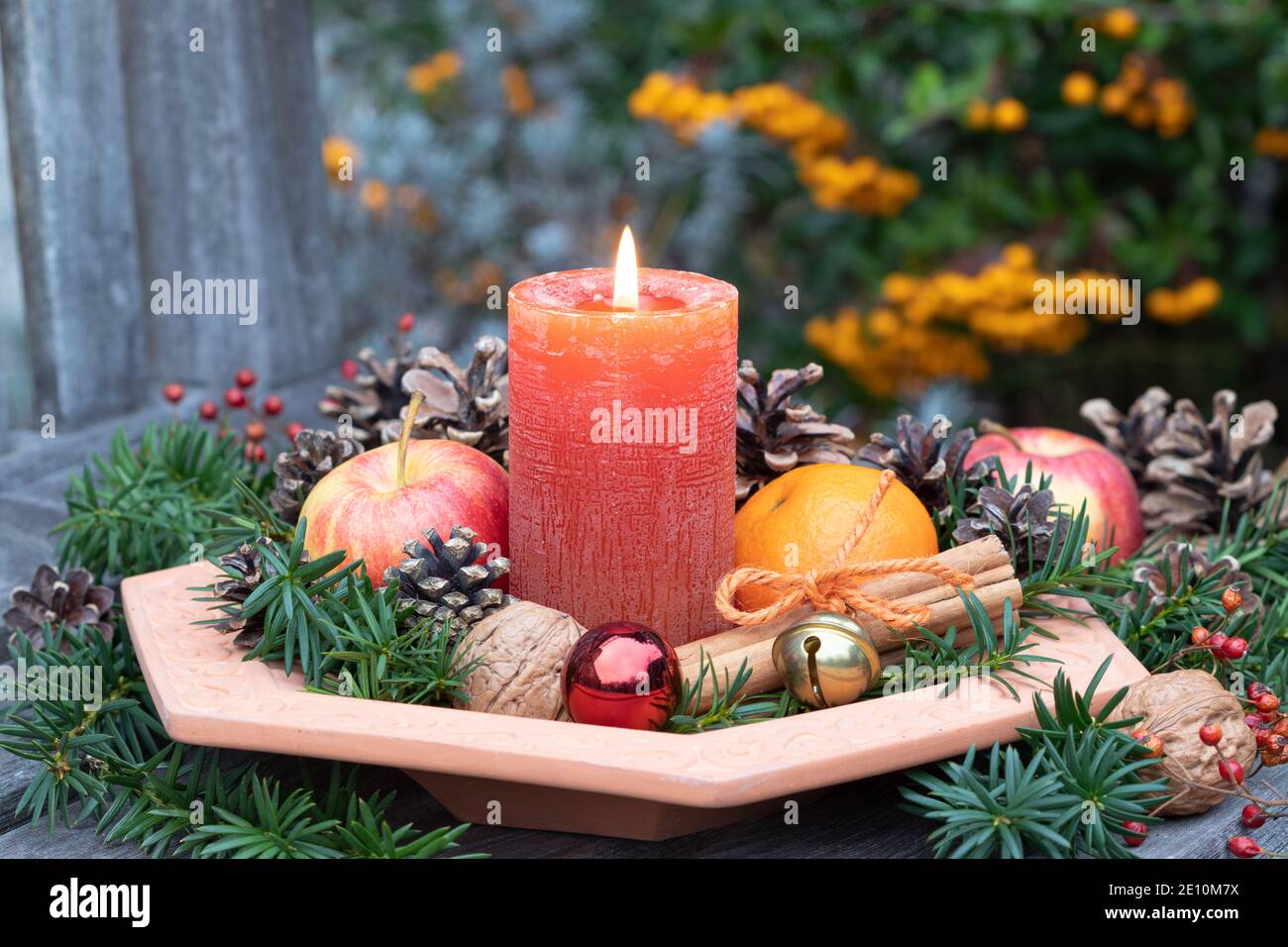 weihnachtsdekoration mit Kerze, Tannenzapfen, Apfel und Mandarine im Teller Stockfoto