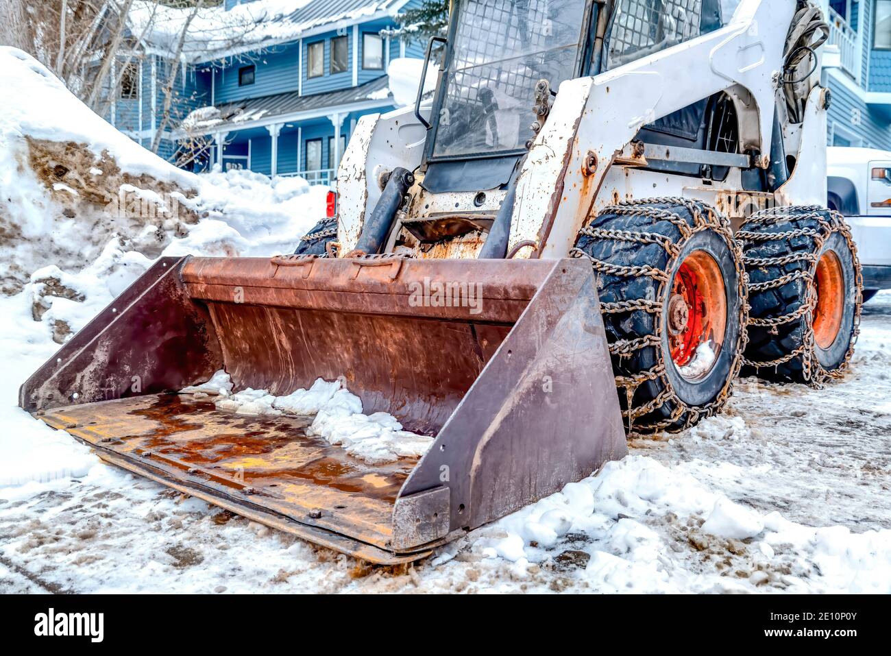 Bulldozer mit rostigen Klinge und Ketten auf den Rädern gegen Haus mit blauer Wand Stockfoto