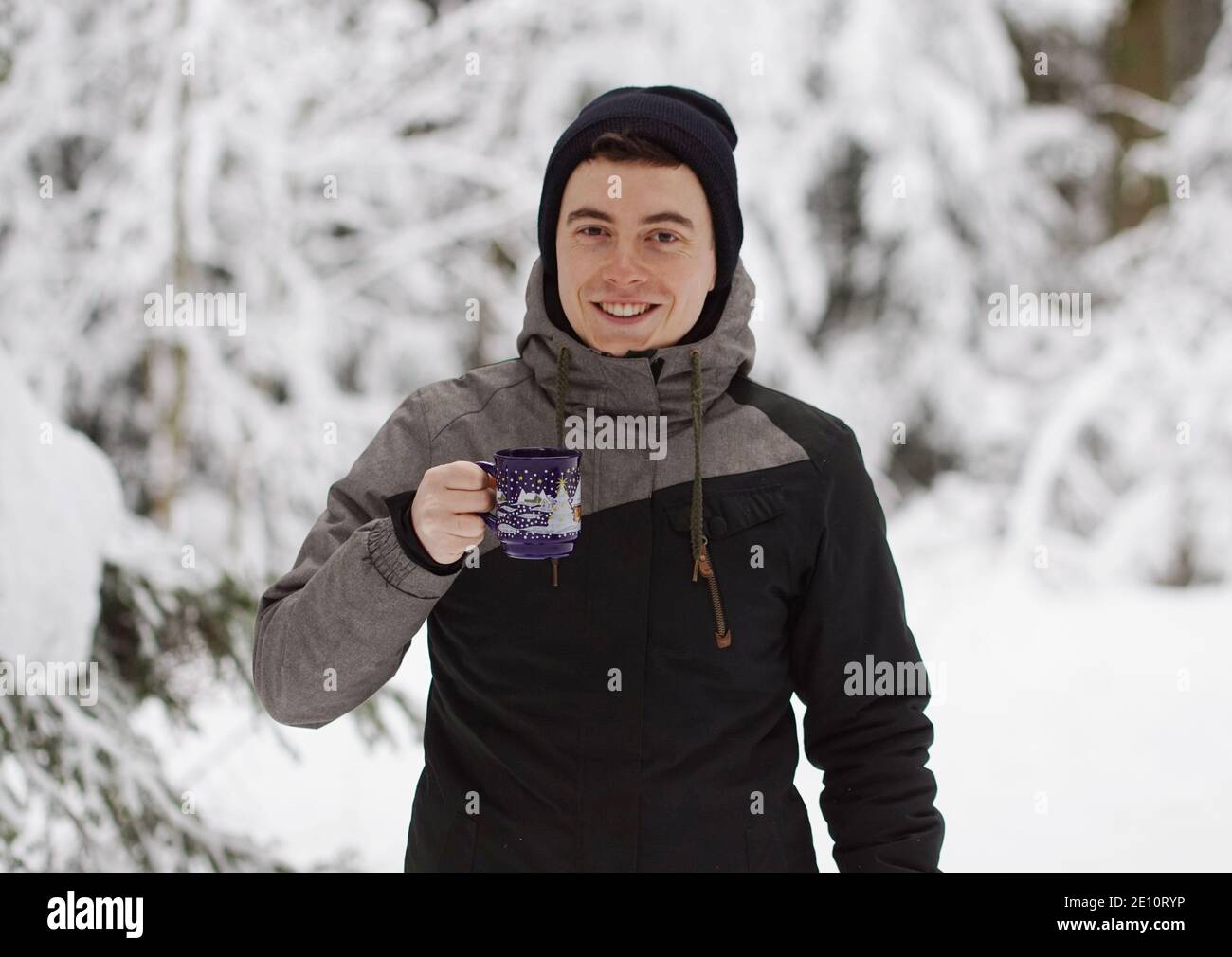 Winter Time - Mann im Schnee, Aufwärmen mit einem heißen Getränk. Eine Tasse Tee oder Glühwein halten. Stockfoto