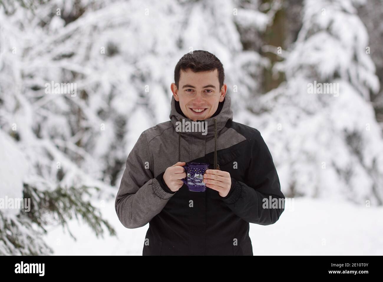 Winter Time - Mann im Schnee, Aufwärmen mit einem heißen Getränk. Eine Tasse Tee oder Glühwein halten. Stockfoto