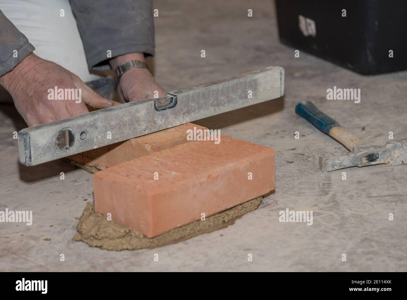 Mason Baut Ziegelwand Und Misst Mit Spirit Level - Nahaufnahme Stockfoto