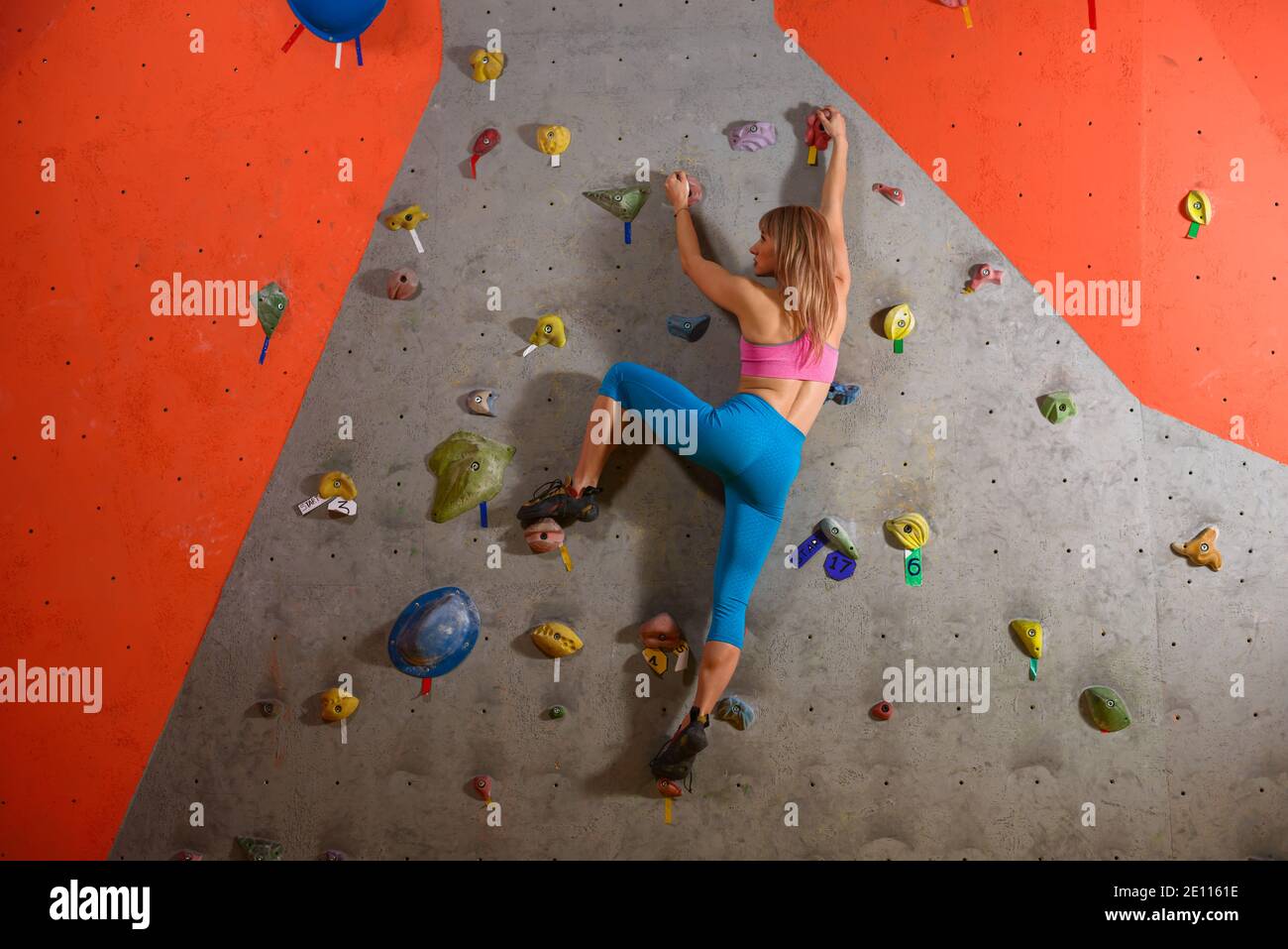 Junge Klettererin Bouldern in der Kletterhalle. Extreme Sport und Indoor Climbing Konzept Stockfoto