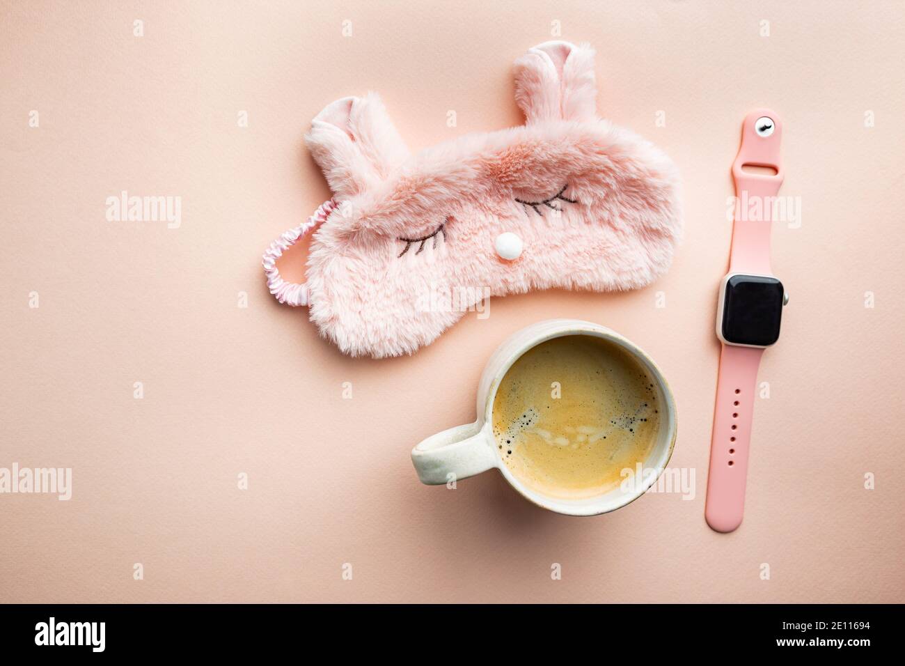 Schlafmaske und Kaffeetasse auf rosa Hintergrund. Das Konzept des Starts eines neuen Tages, guten Morgen oder Ende des Tages, späten Abend. Stockfoto