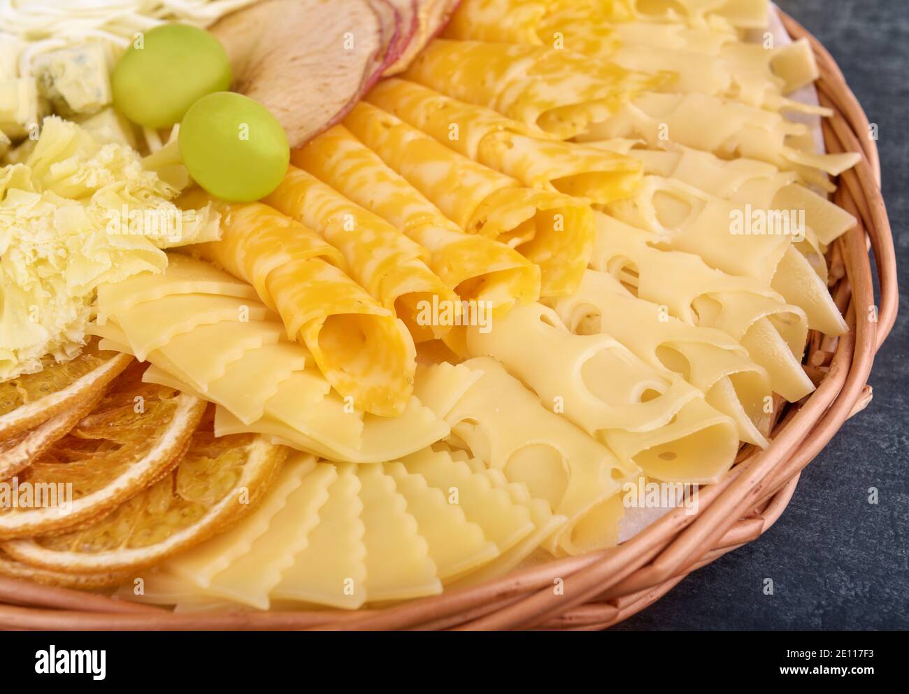 Verschiedene Käsesorten mit getrockneten Orangenscheiben, getrockneten Apfelscheiben und Trauben in Nahaufnahme Stockfoto