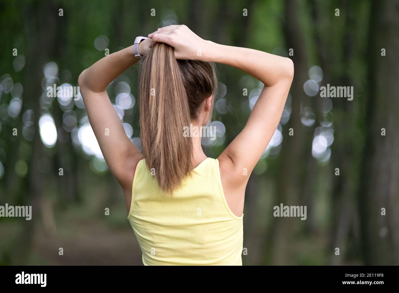 Junge Frau bindet ihre langen Haare stehen im Freien. Stockfoto