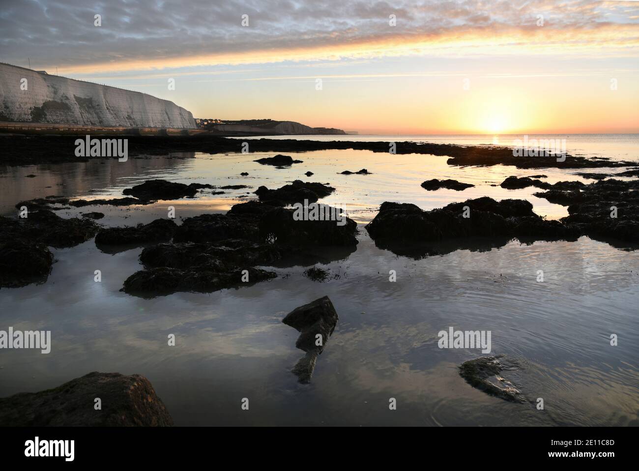 Glühende Sonne über felsiger Küste mit heiterem Himmel und reflektierendem Wasser in der Nähe von Rottingdean, East Sussex, England, Großbritannien Stockfoto