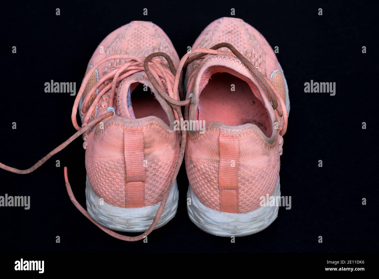 Nahaufnahme von schmutzigen Pfirsich Sneakers nach einem Lauf auf schwarzem Hintergrund. Stockfoto
