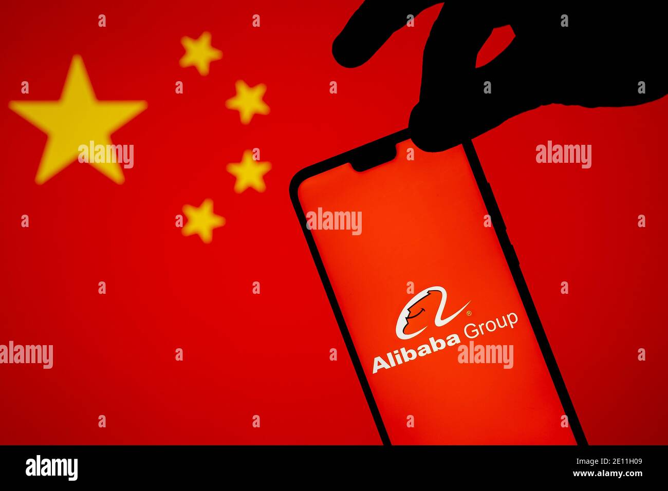 Stafford, Vereinigtes Königreich - 3. Januar 2021: Alibaba-Logo auf einer Silhouette des Smartphones, die auf der Kante gehalten wird. Konzept für staatliche Ermittlungen Stockfoto