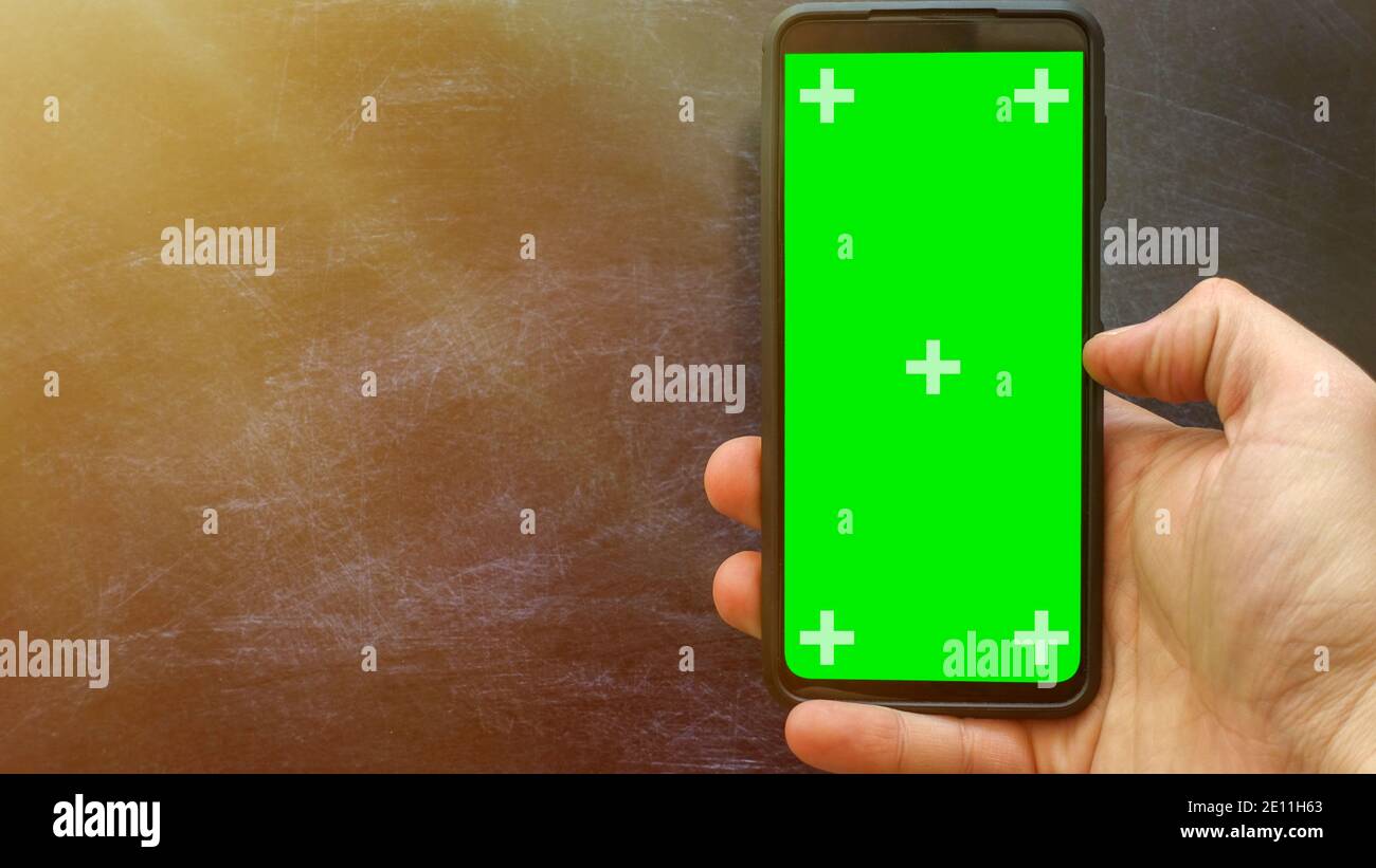 Vertikales grünes Handy mit Platz für Text und Design. Werbung für mobile Apps. Junger Mann mit einem modernen Smartphone. Chroma-Taste Stockfoto