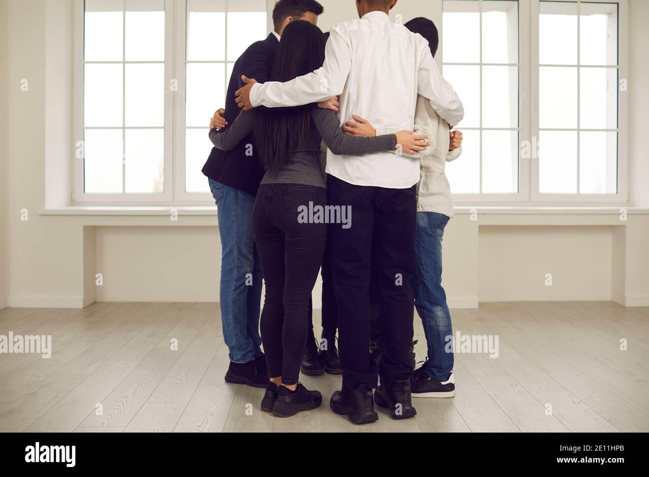 Junge Menschen umarmen einander in Corporate Work Meeting oder In der Gruppentherapie-Sitzung Stockfoto