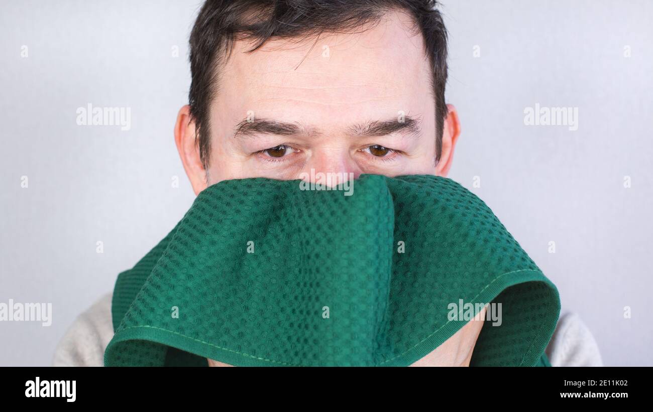 Nahaufnahme eines kaukasischen Mannes, der sein Gesicht mit einem grünen Handtuch abwischt. Stockfoto