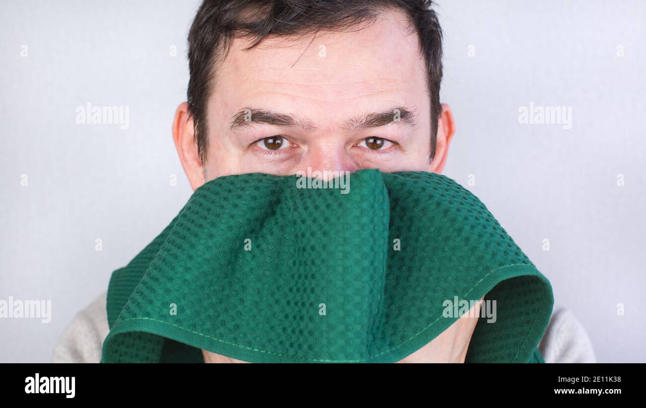 Nahaufnahme eines kaukasischen Mannes, der sein Gesicht mit einem grünen Handtuch abwischt. Stockfoto