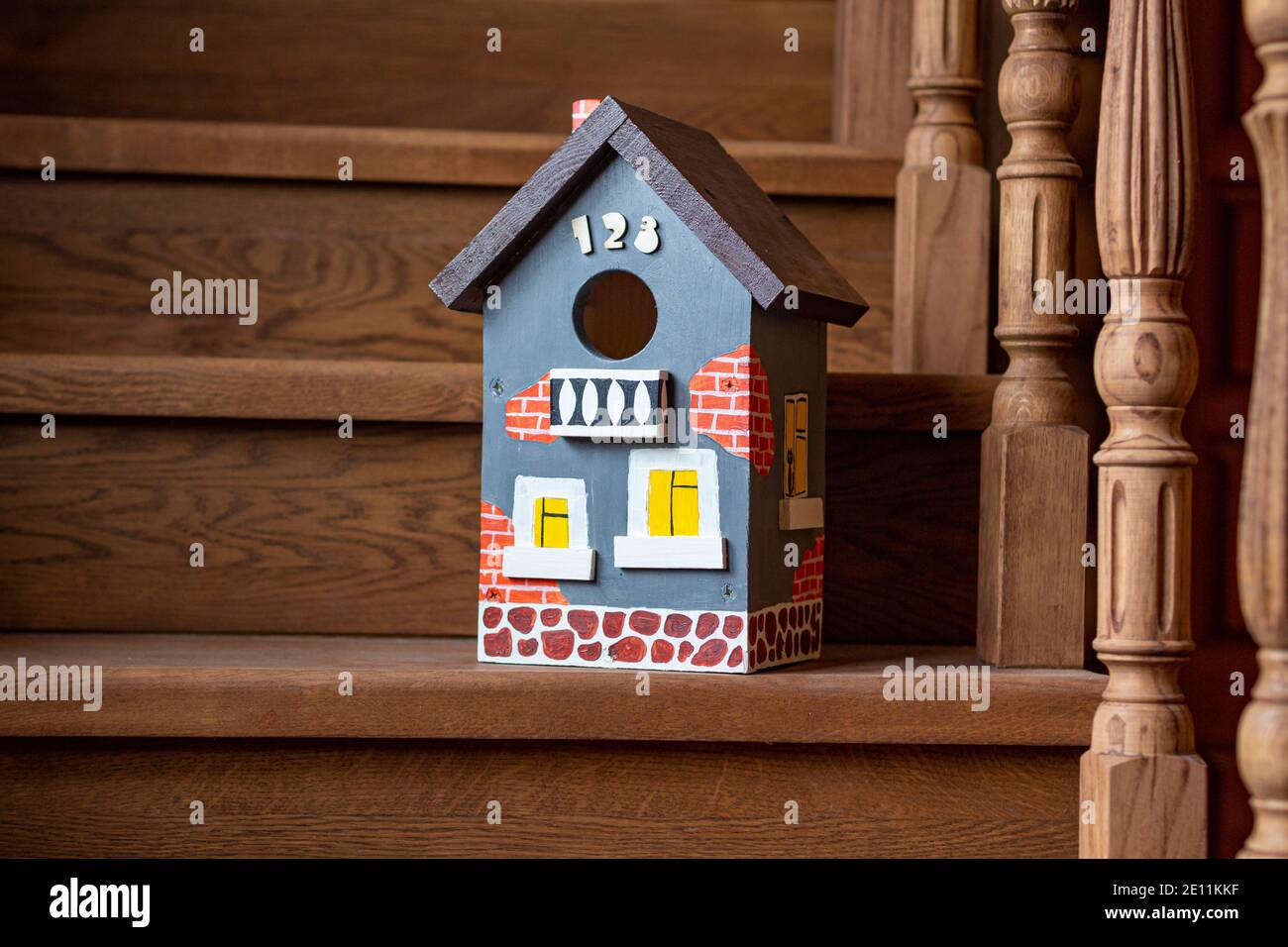 Auf der Holztreppe eines Hauses steht eine handbemalte, lebendige Vogelhaus-Nahaufnahme. Die Pflege der Vögel, die Natur. Zimmerei arbeiten. Stockfoto