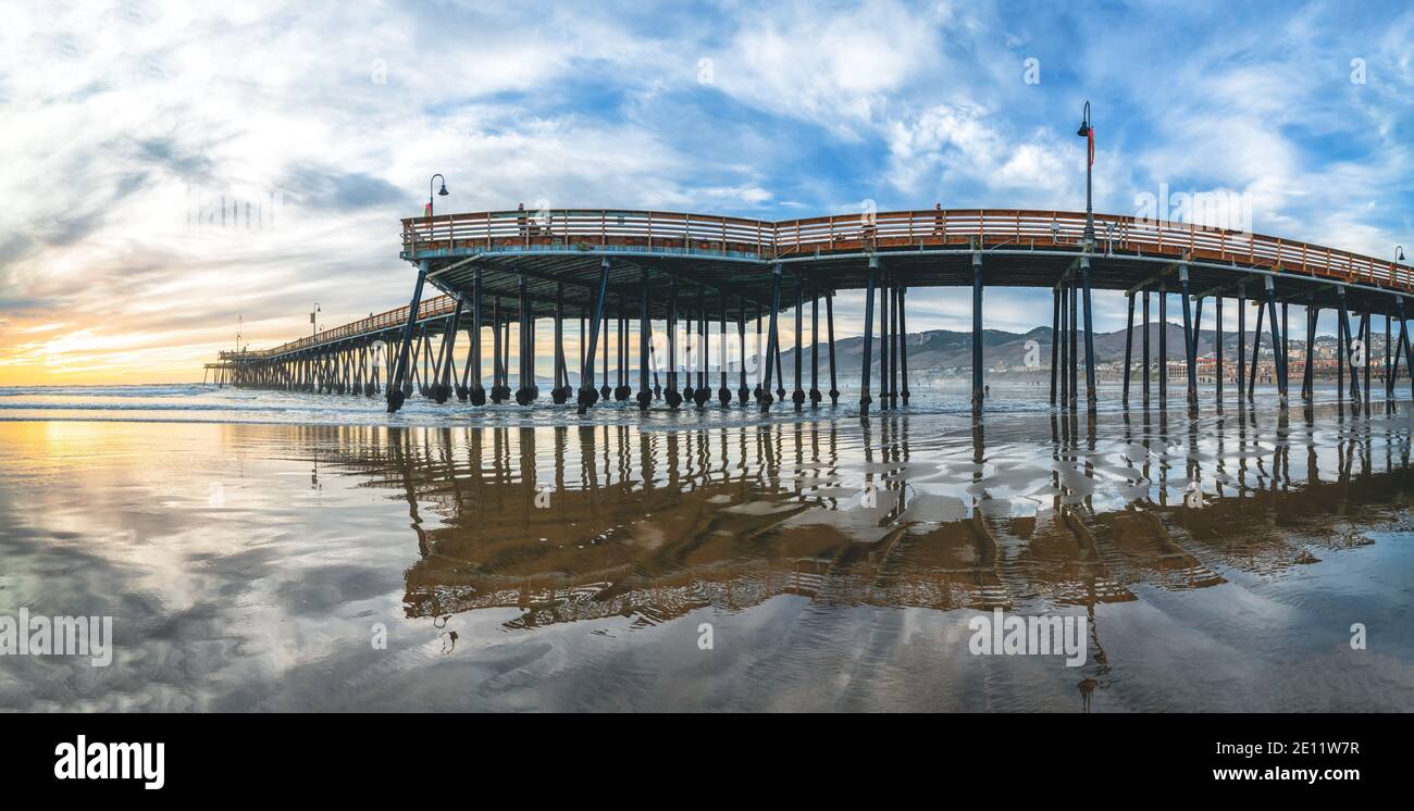 Pismo Beach, California/USA - 1. Januar 2021 Pier, der sich zur untergehenden Sonne hin erstreckt, Panorama. Ein ikonischer kalifornischer Holzpier bei 1, 370 Fuß Lo Stockfoto