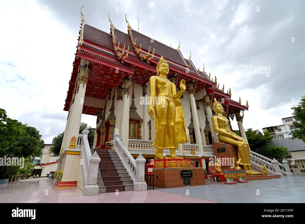 Bilder von Walking Buddha und sitzenden Buddha im Wat Sitaram, einem thailändischen Kloster in Bangkok. Die Ordinationshalle des Tempels hat ein Dach im chinesischen Stil. Stockfoto