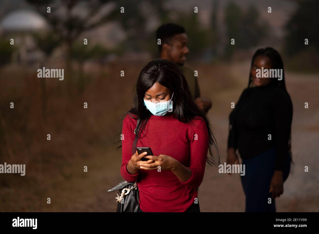 Eine afrikanische Dame, die ihr Handy benutzt, um zu plaudern Stockfoto