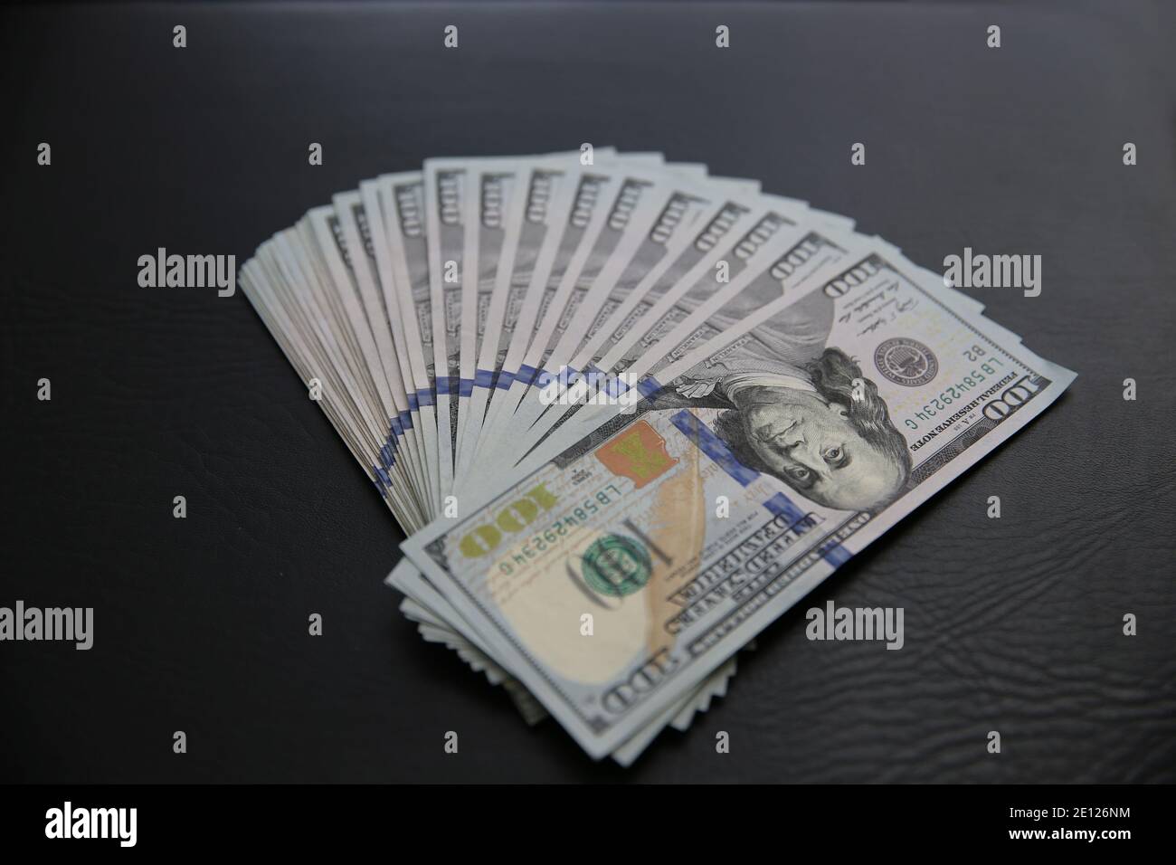 Set von 100 US-Dollar Scheine auf schwarzem Leder Hintergrund. Viele amerikanische Banknoten Stockfoto