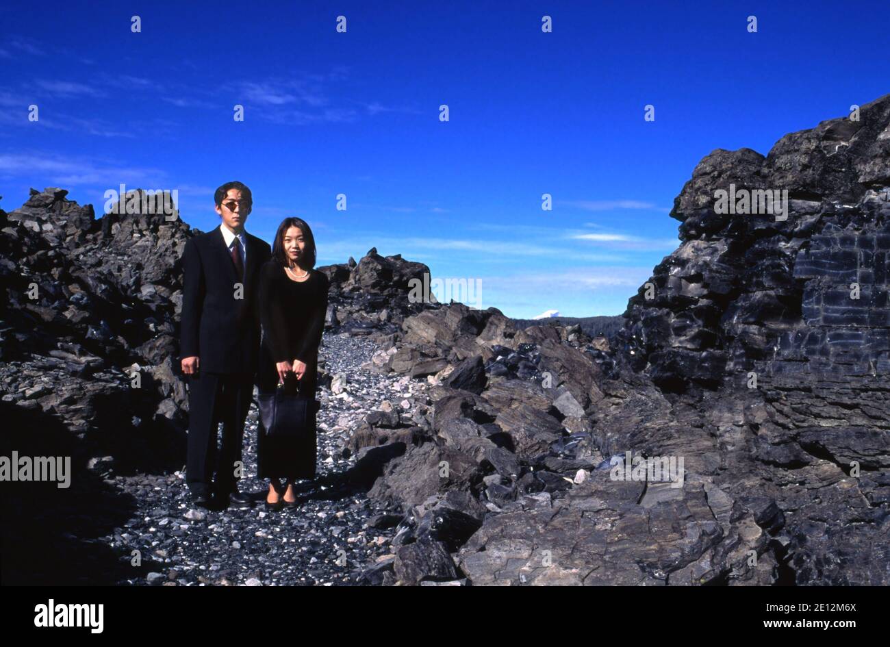 Junges asiatisch-amerikanisches Paar (Teil einer Hochzeitsfeier) auf dem Weg durch Obsidian Flow am Newberry Crater in Oregon. Modellversion #s 9601A und 9601B. Stockfoto