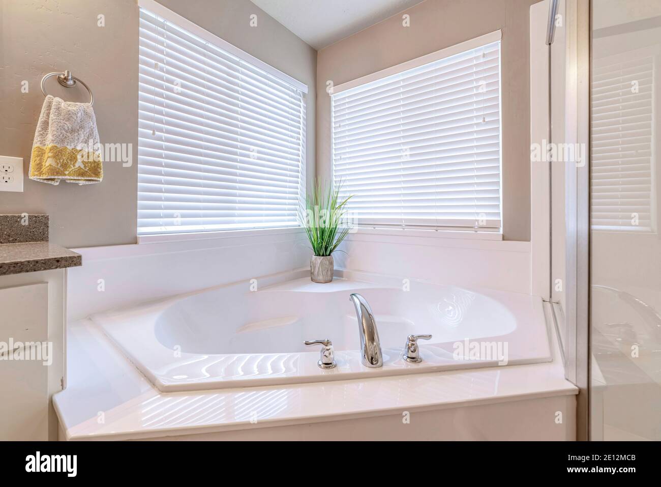 Eingebaute Badewanne an der Ecke eines gut beleuchteten Home Badezimmer mit zwei Fenstern Stockfoto