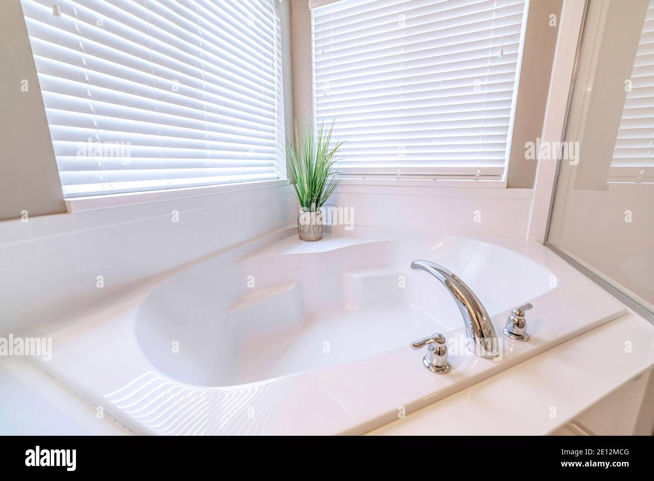 Eingebaute Badewanne in einem Badezimmer mit Innenanlage und Zwei Fenster mit Jalousien Stockfoto