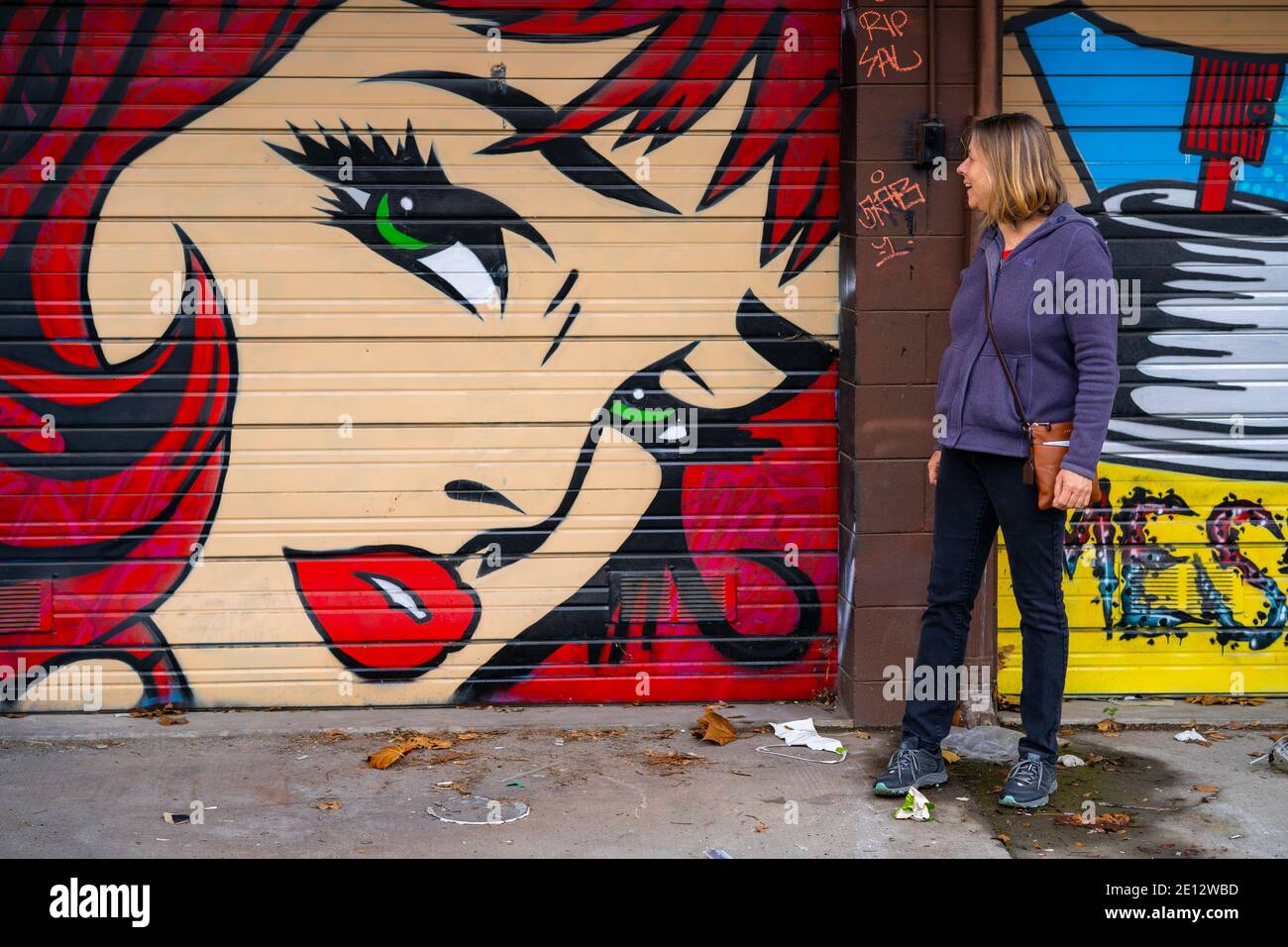 Frau mittleren Alters bewundert Street Art / Graffiti Stockfoto