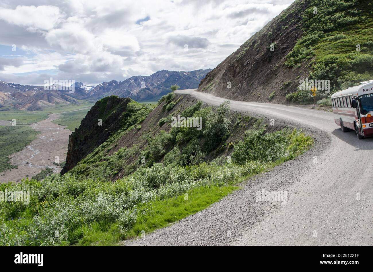 Ein Parkbus fährt am wolkigen Sommertag im Denali National Park im Inneren Alaskas entlang des hohen Bergrückens der Denali Park Road mit Blick auf das Tal. Stockfoto