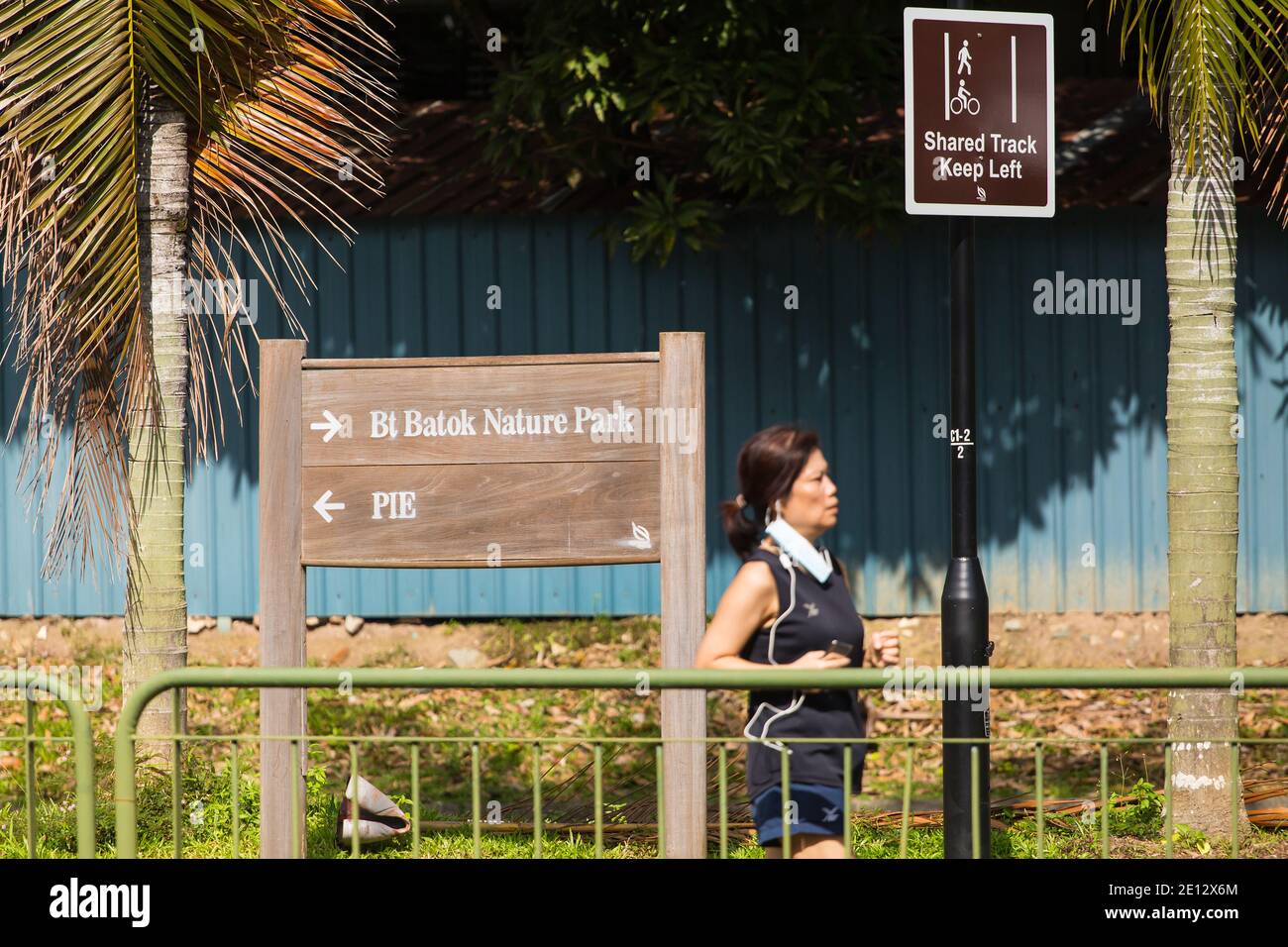 Eine Chinesin läuft an einem Schild an einem Außenparkanschluss in Singapur vorbei. Stockfoto