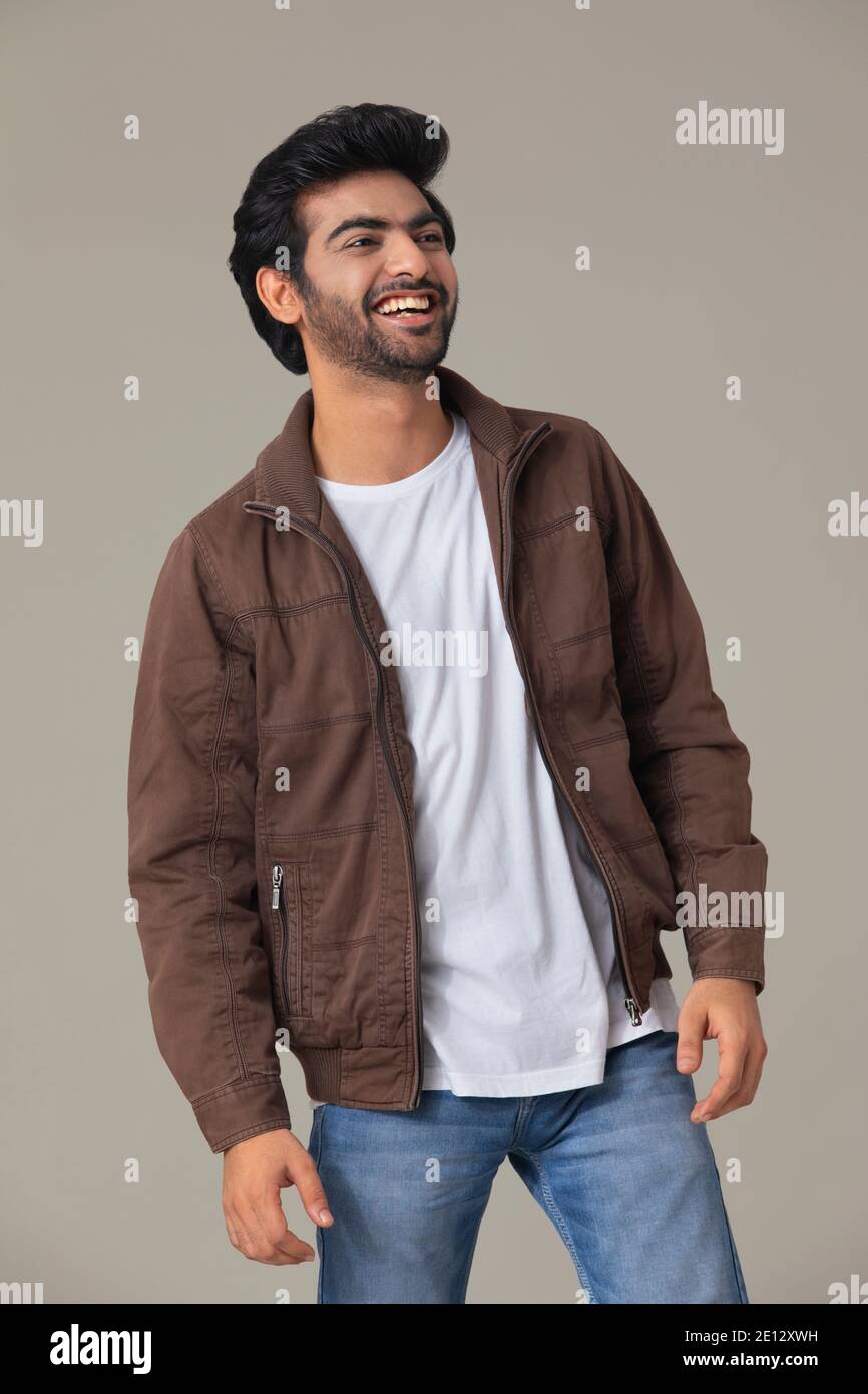 EIN JUNGER MANN SCHAUT ZUR SEITE UND LACHT Stockfoto