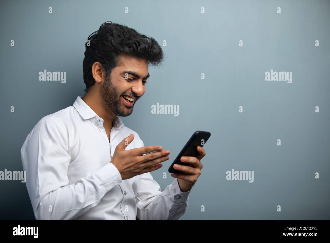 EIN BÜROLEITER FREUT SICH ÜBER VIDEOKONFERENZEN MIT DEM MOBILTELEFON Stockfoto