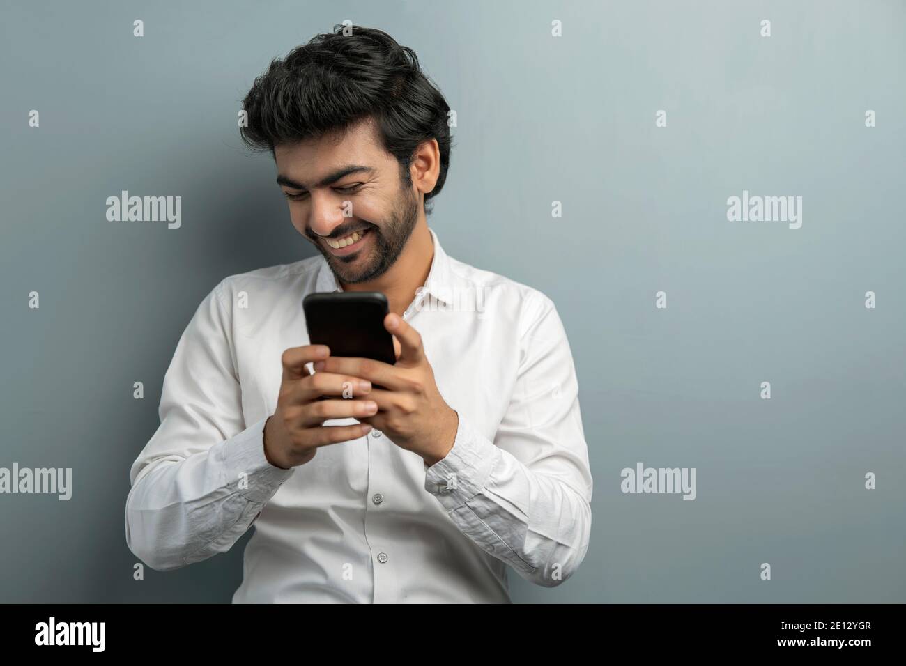 EIN JUNGER MANAGER LACHT WÄHREND ER WÄHREND DES VIDEOS MIT DEM MOBILTELEFON TELEFONIERT KONFERENZEN Stockfoto