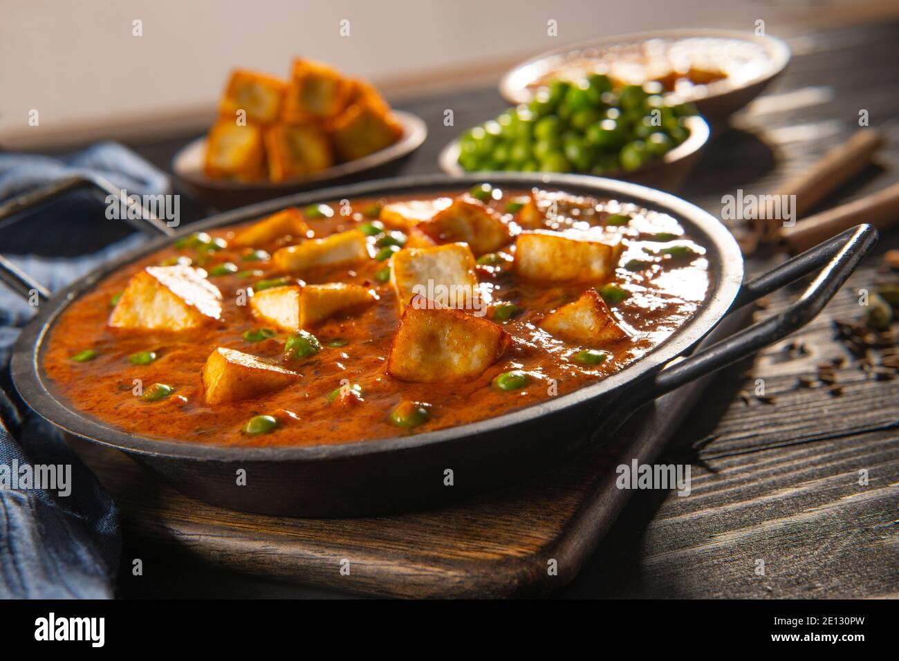 Mattar Paneer oder Hüttenkäse mit Erbsen. Eine vegetarische indische Delikatesse, mit rohen Erbsen und gebratenem Paneer (Hüttenkäse) im Hintergrund. Stockfoto